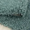 A close-up view of a shaggy rug with a teal color. Produktbild-Vorschau