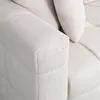 A close-up view of a textured, beige sofa armrest and a pillow. Voir les images du produit