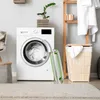 A laundry room scene with a washing machine, laundry basket, and a folding ironing board. Produktbild-Vorschau
