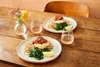 Two plates of food with wine glasses on a wooden table. Anteprima dell’immagine prodotto