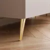 A close-up view of the lower section of a TV lowboard, showing one of its gold-colored metal legs resting on a wooden floor. Voir les images du produit
