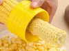 A hand is using a yellow corn peeler to remove kernels from a cob of corn, with a pile of corn kernels in the foreground. Produktbild-Vorschau
