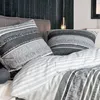 A close-up view of bedding with pillows on a bed, with a dark wooden wall in the background. Produktbild-Vorschau
