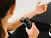 A person is using a black massage gun on their arm. Produktbild-Vorschau