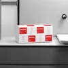 A stack of paper towel packages on a shelf in a bathroom or washroom setting. Náhled obrázku produktu