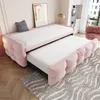 A pink sofa bed with an extended pull-out mattress, set in a room with a patterned rug and a framed picture on the wall. Produktbild-Vorschau