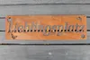 A rusty metal sign with the word "Lieblingsplatz" cut out, placed on a dark wooden surface. Produktbild-Vorschau