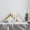 Two Christmas candle arches are displayed on a white tablecloth, with silver ornaments in the foreground. Podgląd zdjęcia produktu