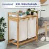 A bamboo laundry basket with two pull-out white fabric bags, shown with folded towels and decorative items on the top shelf. Produktbild-Vorschau
