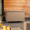 A beige woven storage box sits on a patio in front of a wooden wall. Oranges are visible in the foreground. Náhľad obrázku produktu
