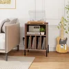 A record player stand with vinyl records, a radio, and a plant on it, placed in a living room next to a sofa and a guitar. Voir les images du produit