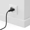A black power cord plugged into a white electrical outlet on a white wall. Náhľad obrázku produktu