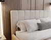 A close-up view of a bed with a beige upholstered headboard and white bedding. Náhled obrázku produktu