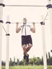 A man is doing pull-ups on a bar outdoors. Náhľad obrázku produktu