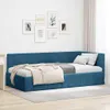 A blue velvet corner bed frame with a headboard, made up with bedding and pillows, is shown in a room setting with framed artwork on the wall and curtains in the background. Produktbild-Vorschau