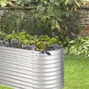 A raised garden bed filled with plants, set in a garden with a stone wall in the background. Produktbild-Vorschau