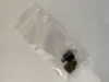 Two small, dark-colored metal parts are inside a clear plastic bag, lying on a white surface. Produktbild-Vorschau