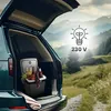 A mini refrigerator filled with drinks and fruit is placed in the open trunk of a car, set against a scenic mountain landscape. Podgląd zdjęcia produktu
