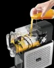 A hand is pouring orange juice into a juicer, showing the juicing process. Produktbild-Vorschau