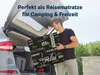 A man is loading a folded mattress into the trunk of a car, suggesting it's for travel or outdoor activities. Produktbild-Vorschau