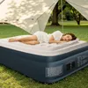 A woman sleeping on an air mattress outdoors under a canopy. Produktbild-Vorschau
