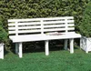 A white plastic garden bench sits on a green lawn in front of a dense green hedge. Anteprima dell’immagine prodotto