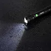 A black flashlight is lying on a wet black surface, with its light beam illuminating the water droplets. Náhled obrázku produktu