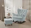 A light blue upholstered rocking chair with an ottoman in a well-lit room with sheer curtains and a window view. Voir les images du produit