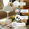 A white mushroom-shaped table lamp is shown on a table next to a candle and books, with callouts highlighting its features. Produktbild-Vorschau