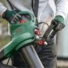 A person wearing gloves is holding a green Bosch leaf blower. Produktbild-Vorschau