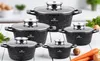 A set of five black pots with speckled marble coating and glass lids, arranged on a white wooden surface. Carrots and potatoes are placed in the foreground. Náhľad obrázku produktu