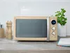 A retro-style cream microwave oven is displayed on a countertop with a white subway tile backsplash. Náhled obrázku produktu