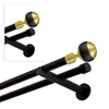 A close-up view of a double curtain rod with a black matte finish and gold accents on the finials. Produktbild-Vorschau
