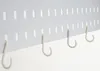 A close-up view of white hooks attached to a white pegboard. Anteprima dell’immagine prodotto