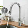 A kitchen faucet with water running into a sink, with decorative jars in the background. Náhled obrázku produktu