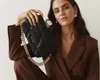 A woman is posing with a black handbag. Produktbild-Vorschau