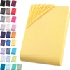 A folded yellow fitted sheet is shown on the right side of the image, with a grid of various colored fitted sheets displayed on the left side. Produktbild-Vorschau