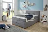 A bedroom scene with a bed, luggage, and decorative items. Produktbild-Vorschau