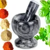 A granite mortar and pestle with various spices and herbs arranged around it. Voir les images du produit