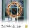 A decorative wreath made of branches and lights hanging on a green door. Produktbild-Vorschau