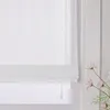 A close-up view of a white sheer Roman blind with vertical stripes, partially covering a window. Produktbild-Vorschau
