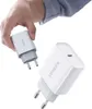 A hand holds a white USB charger while another charger is placed in front of it. Náhled obrázku produktu