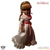 A full-body shot of an Annabelle doll in a white dress with a red sash, standing against a white background. Náhled obrázku produktu