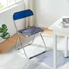 A folding chair is placed on a rug next to a white table. Podgląd zdjęcia produktu