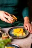 A person is pouring sauce onto a plate of crepes with orange slices. Náhľad obrázku produktu