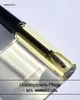 A close-up shot of a cosmetic product, likely an eyebrow serum or oil, in a clear glass bottle with a black applicator wand inside. The product is illuminated by soft light, casting a shadow on a light gray surface. Produktbild-Vorschau