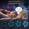 A child sleeping in bed with a soccer ball-shaped night light and a remote control. Produktbild-Vorschau