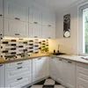 A modern kitchen with white cabinets, a tiled backsplash, and a wooden countertop. A clock with a coffee cup design is hanging on the wall. Náhľad obrázku produktu