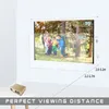 A projector is shown on a table in front of a projection screen displaying a family. Distances are indicated on the screen. Produktbild-Vorschau
