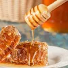 A close-up shot of honeycomb and a honey dipper with honey dripping onto the honeycomb. Podgląd zdjęcia produktu